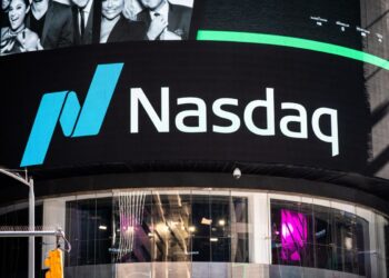 A large digital billboard displays the Nasdaq logo in blue and white, with the interior of the Nasdaq MarketSite in Times Square, New York City visible below. The facade is lit with reflections of pink and other colors, showcasing part of the building at street level. | LESSINVEST