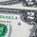 Close-up of two U.S. two-dollar bills, showing part of the intricate design and the number "2" in the corners. Visible details include parts of the Treasury seal and serial number, along with the words "Washington, D.C." printed on the bills—symbols of financial wellness in your hands. | LESSINVEST