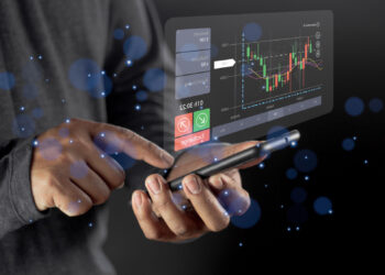A person interacts with a smartphone displaying a holographic trading platform interface. The screen shows a candle chart with financial data and options to accept or decline. Blue light effects surround the scene, emphasizing a futuristic theme. | LESSINVEST