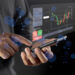 A person interacts with a smartphone displaying a holographic trading platform interface. The screen shows a candle chart with financial data and options to accept or decline. Blue light effects surround the scene, emphasizing a futuristic theme. | LESSINVEST